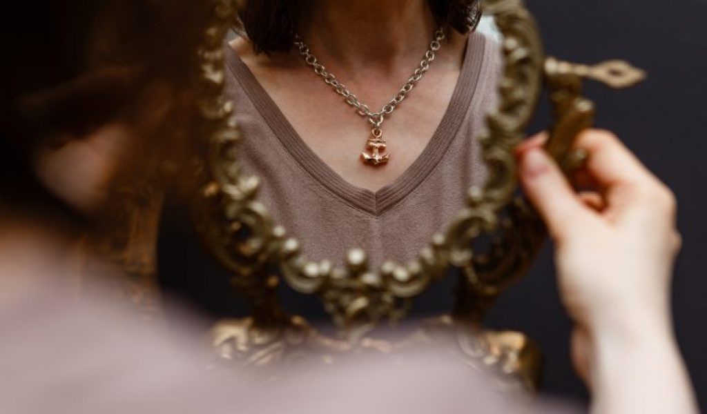 Frau betrachtet Kette im Spiegel